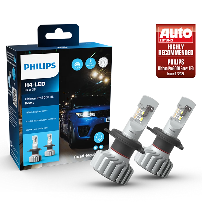 Billede af Philips H4 Ultinon Pro6000 Boost LED pærer med en emballage der viser produktinformation og anbefalinger samt en bil baggrunden i nattemiljø. Pærerne er designet til at forbedre billys med op til 300 procent lysstyrke og har en farvetemperatur på 5800 K for ren hvidt lys.