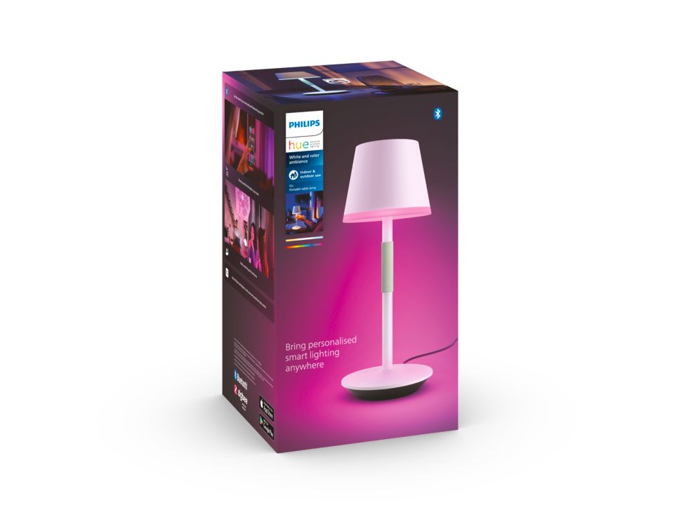 Produktbillede af Philips Hue Go bærbar bordlampe i hvid med en lampe med pink nuancer og en glat base, præsenteret i en attraktiv emballage med farverigt design og illustrative billeder af lampens anvendelse i indendørs og udendørs omgivelser.