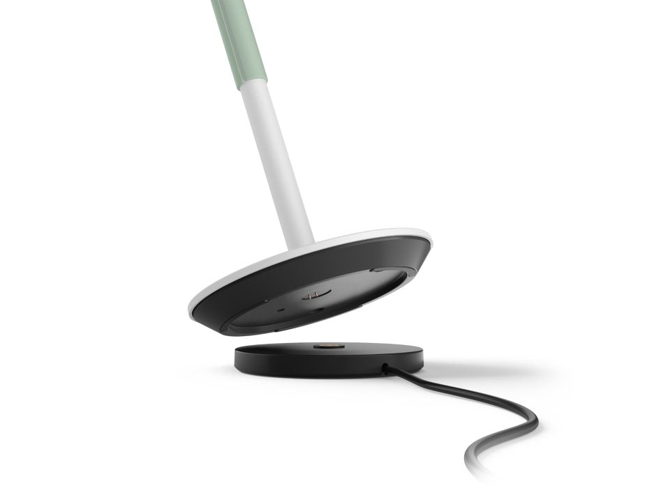Billede af Philips Hue Go bærbar bordlampe i hvid farve med en rund base og grøn stang der viser en kantet ledning fra bunden til opladerstationen