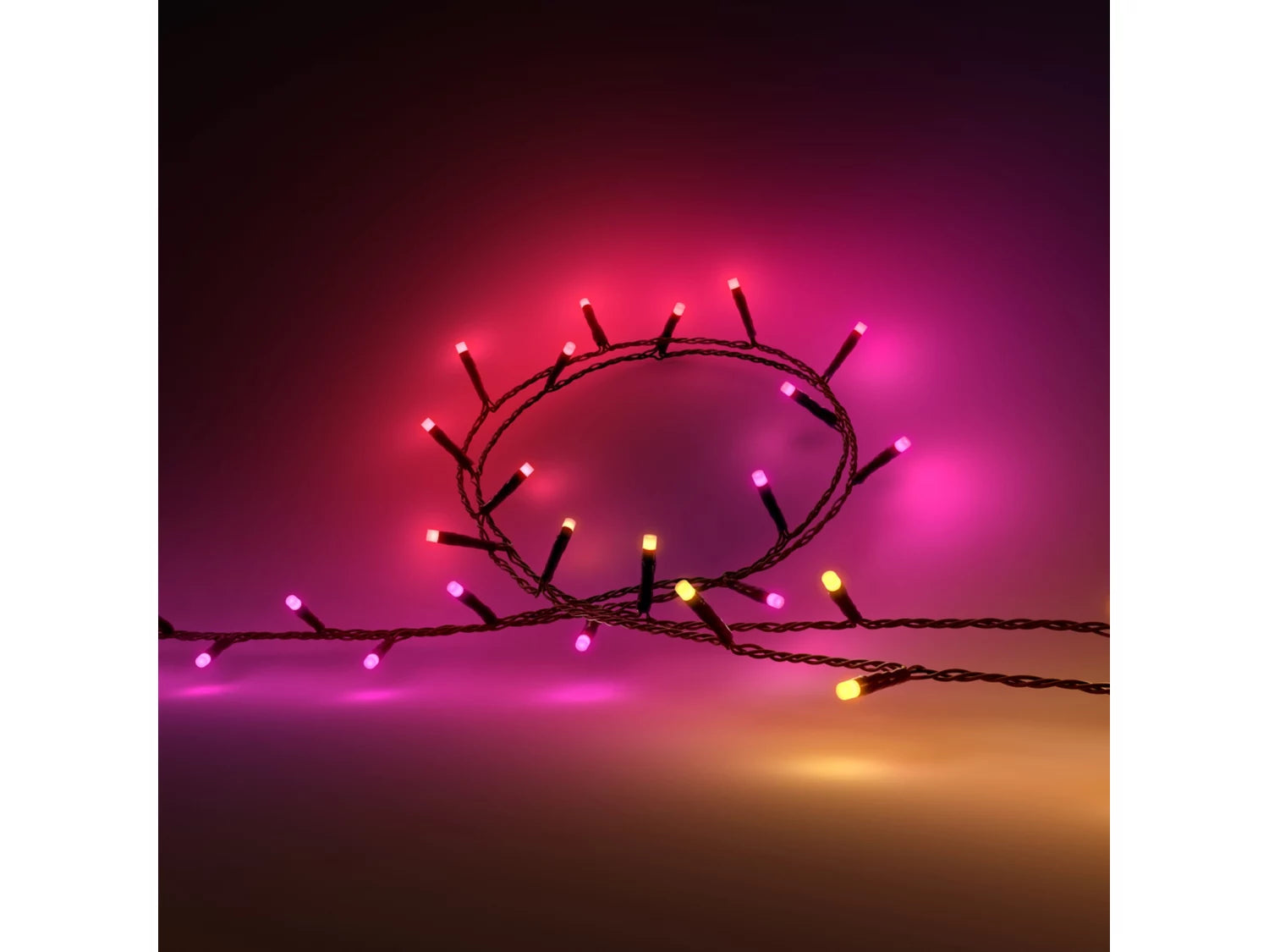 Philips Hue Festavia lyskæde med farverige LED-lys i pink og gul hænger på en mørk baggrund og giver en festlig atmosfære til indretningen