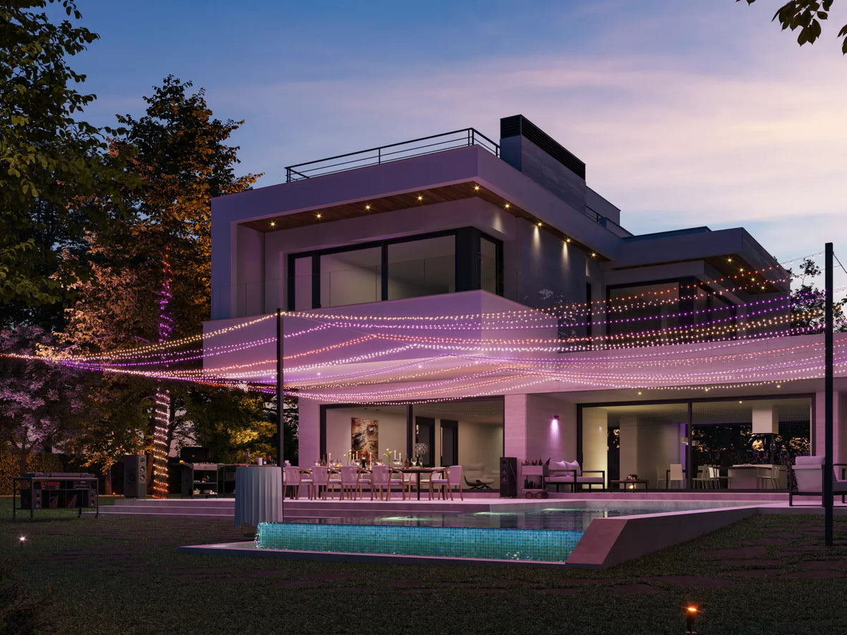Philips Hue Festavia lyskæde med 250 LED'er strækker sig over 20 meter og lyser op i farver omkring en moderne bolig med udendørs terrasse og swimmingpool i skumringen