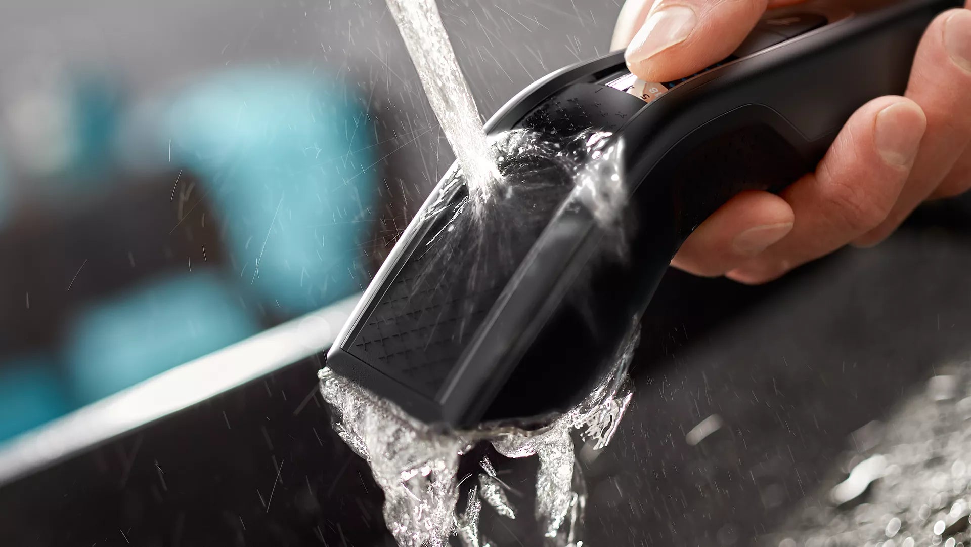 Vaskbar Philips HC5632/15 hårklipper bliver rengjort under rindende vand med fokus på det ergonomiske design og den vandafvisende overflade.