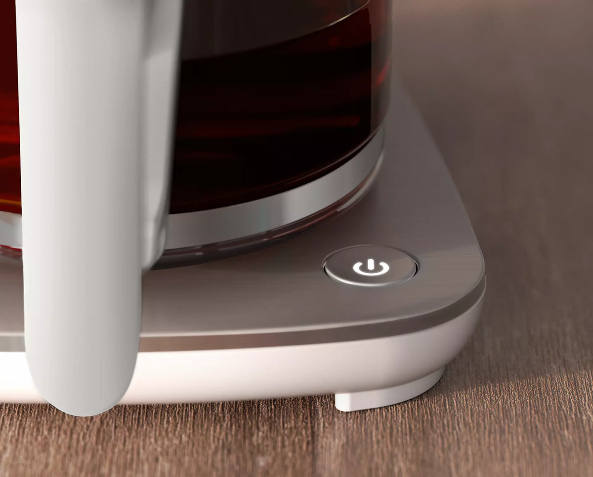 Billede af Philips HD5416/00 Café Gourmet Filter kaffemaskine med en close-up visning af tænd/sluk-knappen og kanten af kanden på en træoverflade.