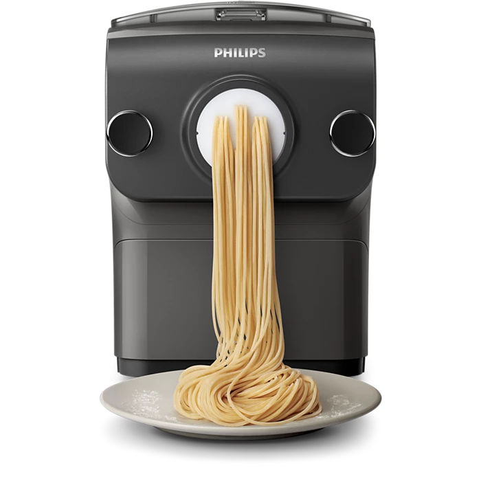 Billede af Philips HR2382/15 Avance Collection pastamaskine med frisklavet spaghetti, der hænger ud fra maskinens udløb og lander på en hvid tallerken med et let drys af mel
