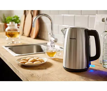 Philips HD9351/90 elkande i metal med en kapacitet på 1,7 liter placeret på et køkkenbord ved siden af en skål med småkager og en kande med te