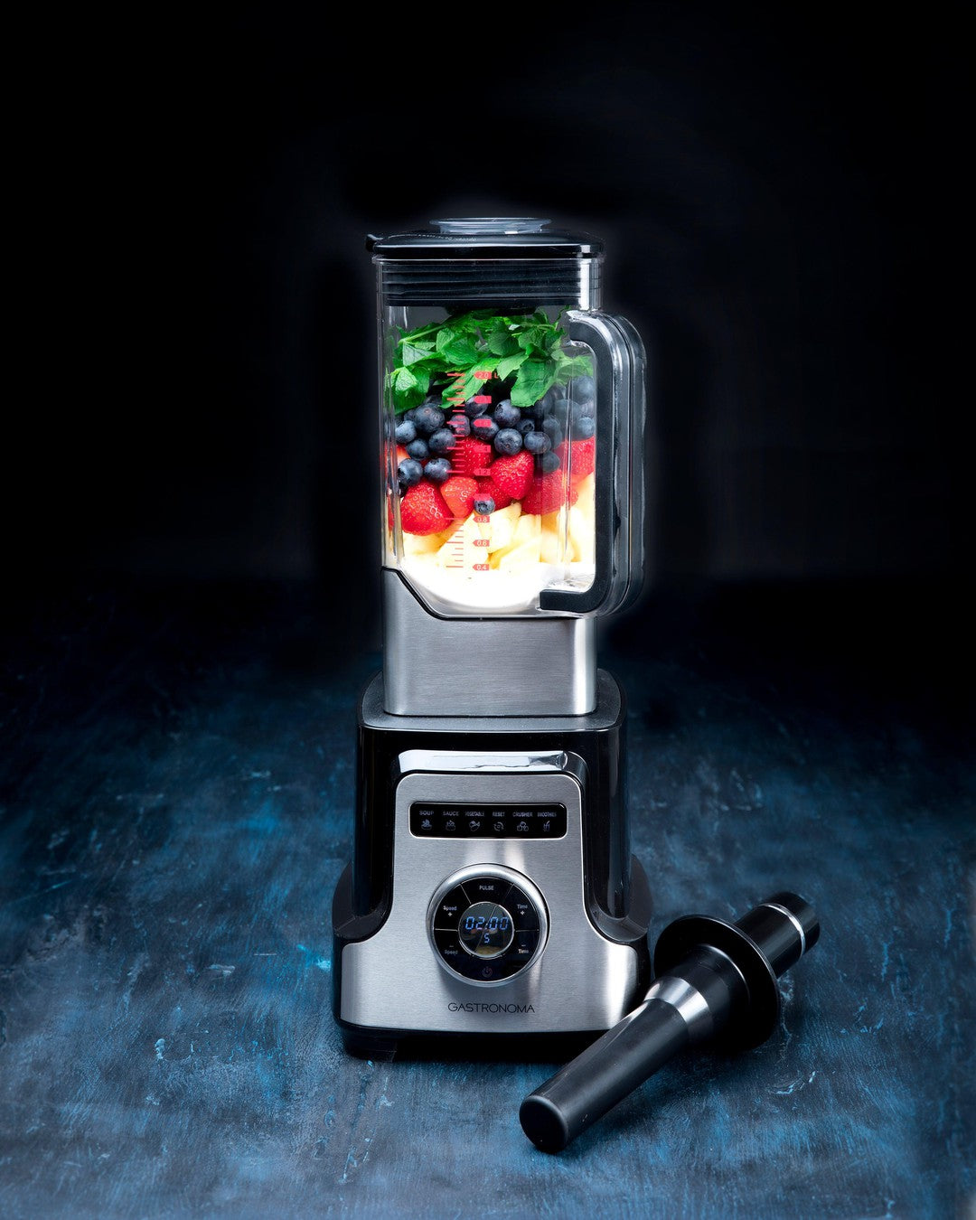 Gastronoma blender med 2 liter Tritan skål uden BPA i sort farve med 2000W effekt der blander frugt og urter synligt i skålen på en sort baggrund