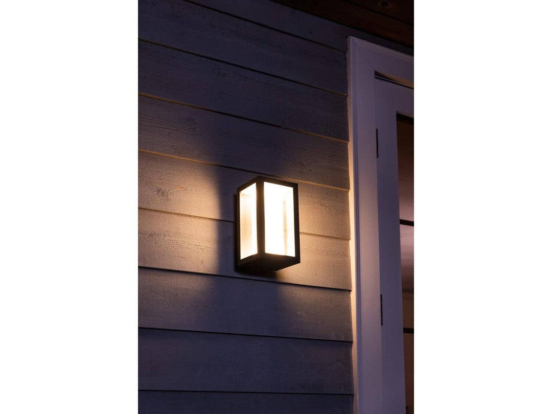 Philips HUE Impress udendørs væglampe monteret på en trævæg med blødt lys der stråler ud fra lampen i en stilfuld og moderne design
