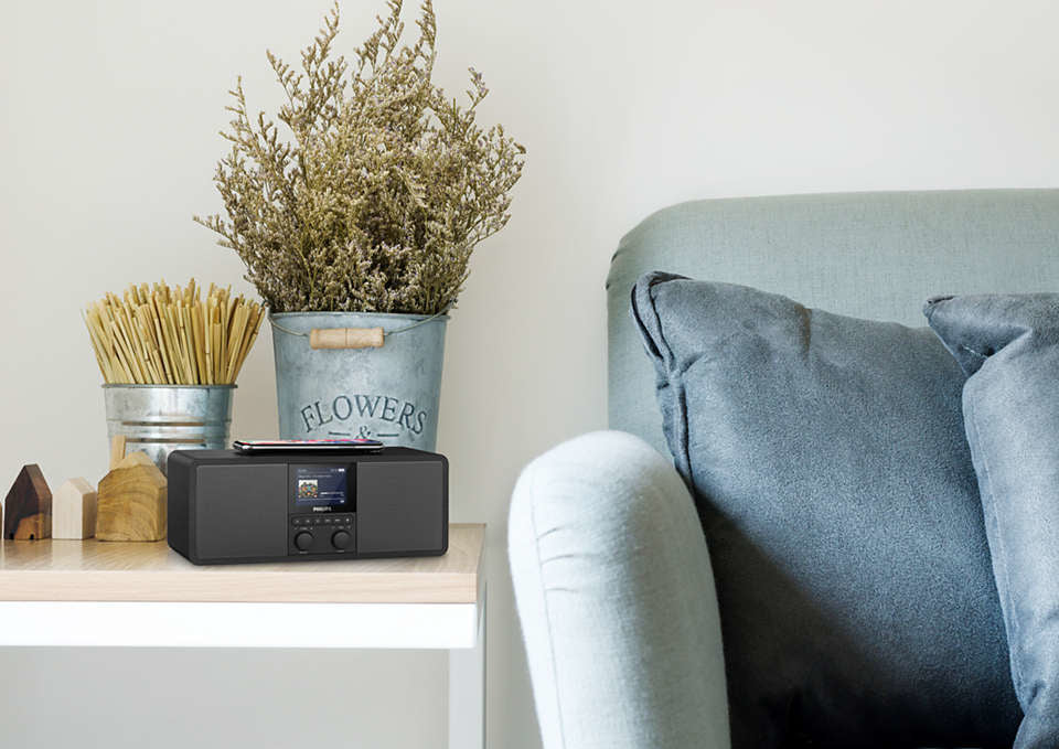 Internetradio fra Philips model TAR8805/10 med DAB+ og FM placeret på et træbord ved siden af en sofa med grå puder og en metalliske potte med tørrede blomster.