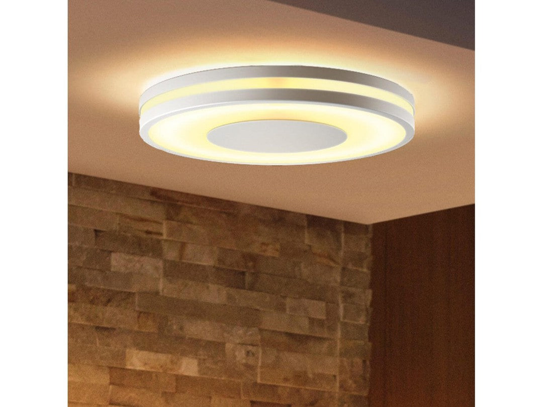 Philips HUE Being loftslampe med en rund, moderne design og blødt lys der stråler fra de indbyggede LED-lamper i en stilfuld hvid og guldfarvet finish, monteret på en væg af natursten