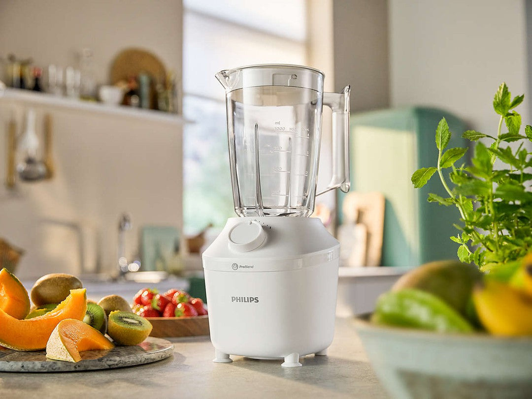 Philips HR2041/00 blender i hvid med en kapacitet på 1,9 liter og en effekt på 450 watt placeret på en køkkenbenk med frugt såsom melon, kiwi og jordbær i nærheden