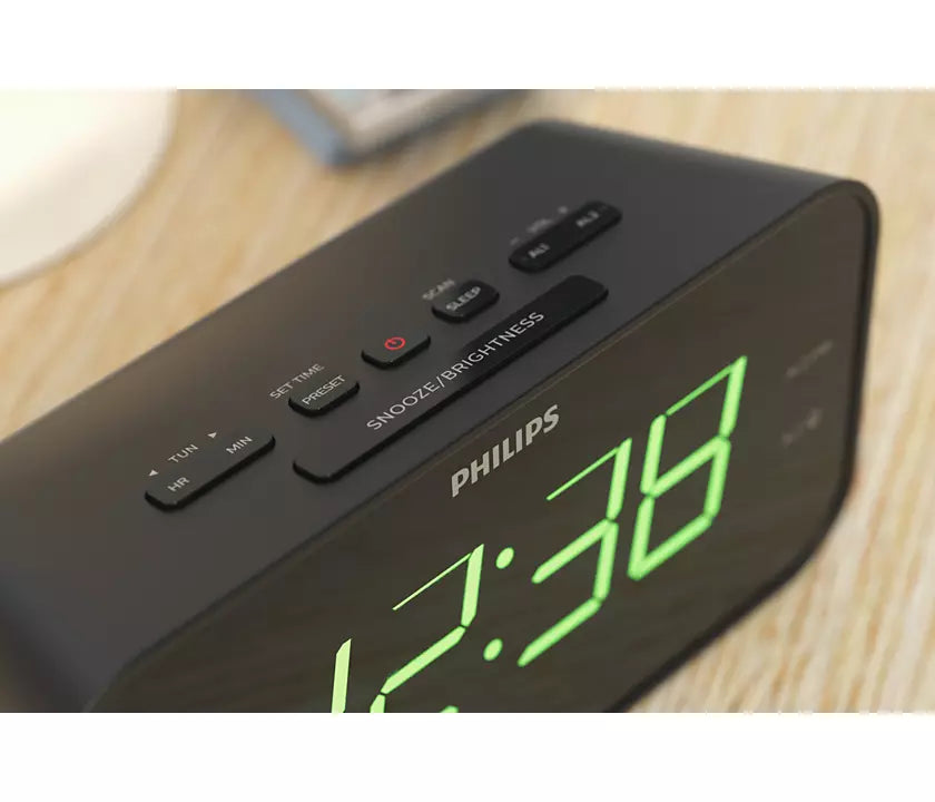 Billede af Philips TAR3306/12 vækkeur med stort og tydeligt digitalt display viser klokken 12:38 samt knapper til indstilling og lysjustering på toppen af en sort enhed.