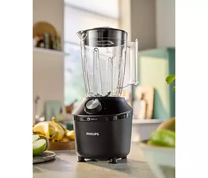 Philips HR2291/01 blender i sort med en gennemsigtig beholder og en drejeknap på fronten står på en køkkenbord, omgivet af frugt og grøntsager i en lys og moderne køkkenindretning
