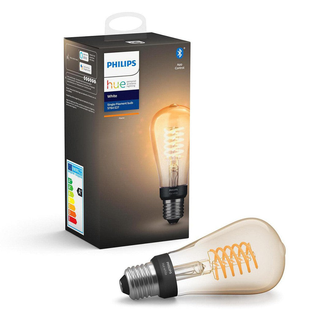 Philips Hue White Filament E27 Edison ST64 Bluetooth pære med synlig filament og varm glød der ligger foran en æske med produktinformation og energi mærkning