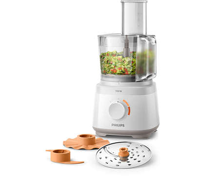 Kompakt Philips HR7310/00 foodprocessor med en kapacitet på 700 W viser en transparent skål fyldt med hakkede grøntsager og er udstyret med en orange drejeknap og tilbehør bestående af skiver og redskaber til opbevaring